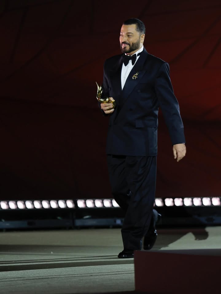 May be an image of suit, dinner jacket, microphone and text