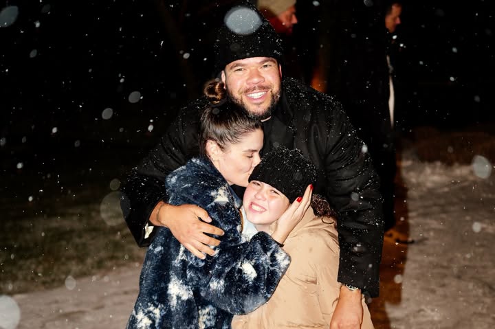 May be an image of smiling, people kissing, snowball, parka, snowsuit, snow and text