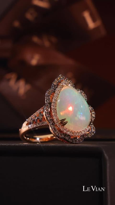 A pear-shaped Neopolitan Opal ring, with diamond wavy halos. It sits atop Le Vian boxes.
