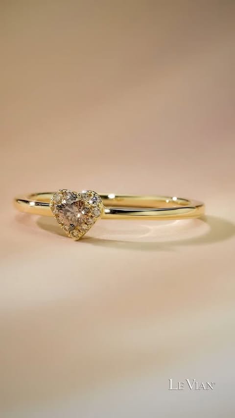 A petite heart ring spins and sparkles. It presents a chocolate diamond surrounded by nude diamonds in a heart, with a polished yellow gold band.