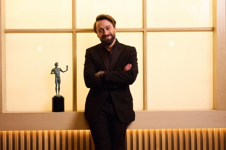 May be an image of one or more people, beard, suit, blazer, dinner jacket and text