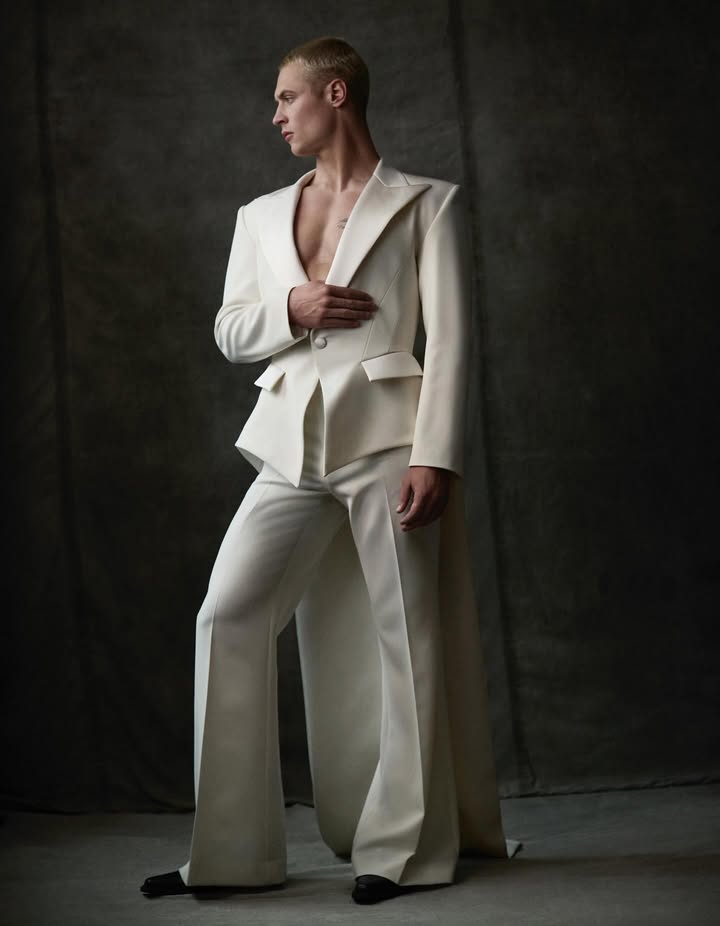 May be an image of overcoat, blazer, dinner jacket, suit and text