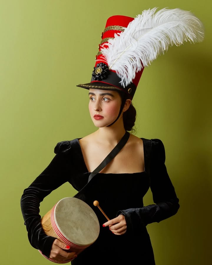 May be an image of headdress, parasol, costume, bowler hat, tambourine and text