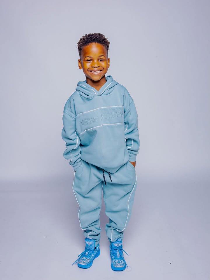 May be an image of child, shoes, drawstring, sweatsuit, sweatpants and text
