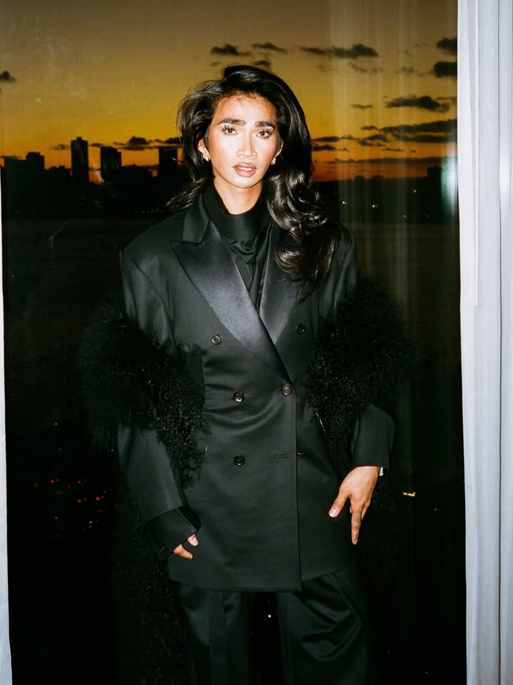 May be an image of one or more people, makeup, overcoat, suit, goosedown coat, fur coat, turtleneck, blazer and text