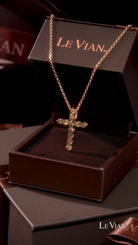 A chocolate brown diamond cross necklace in a box, sparkling as the camera turns.