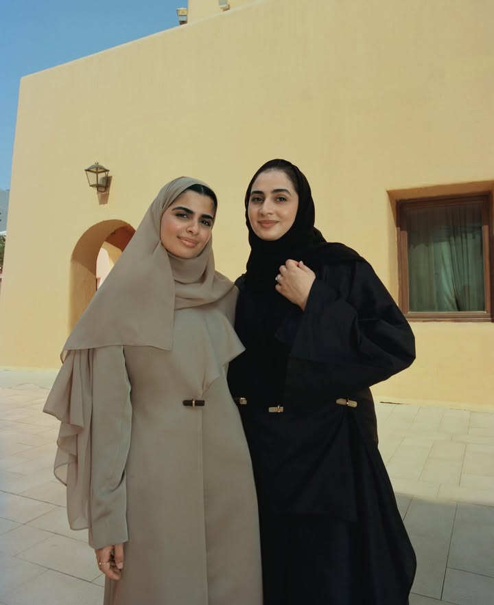 May be an image of one or more people, overcoat, scarf, headscarf, turban and text