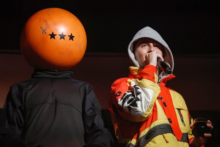 May be an image of beach ball, face mask, costume, raincoat, helmet, parka, gas mask and text