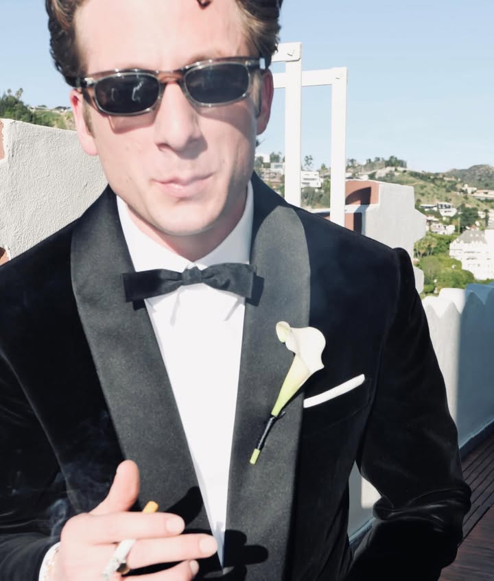 May be an image of smoking, cigar, cigarette, dinner jacket, suit and text