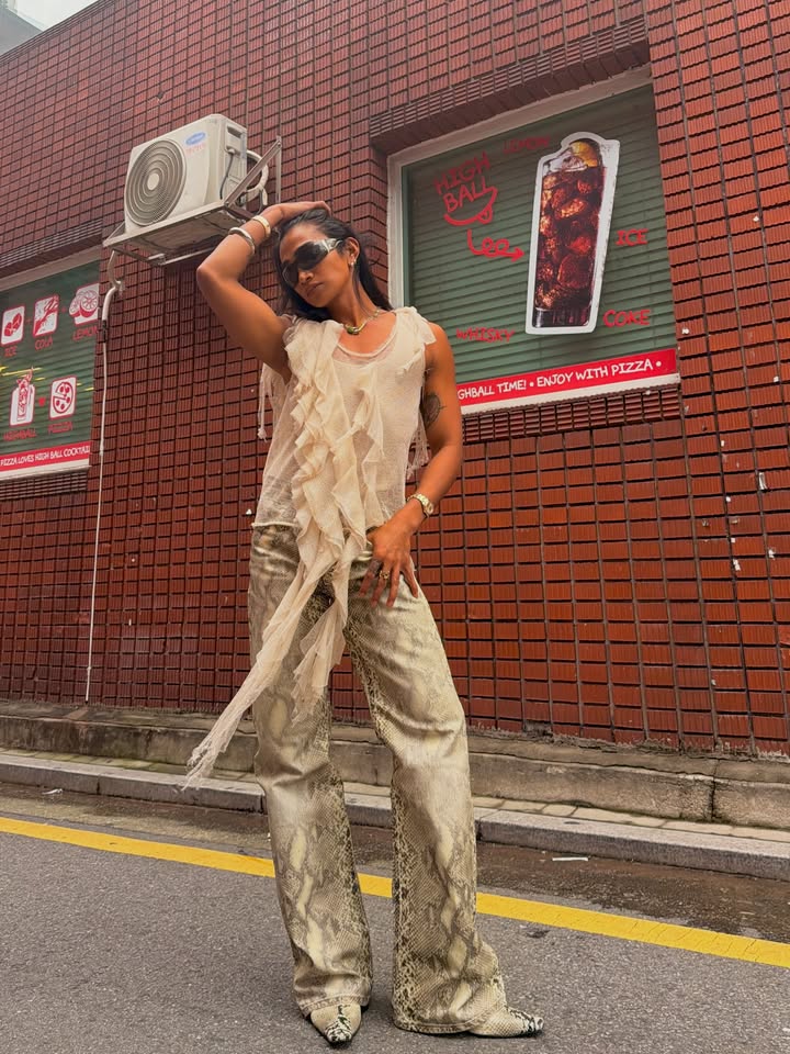 May be an image of jumpsuit, headscarf, fishnet stockings and brick wall