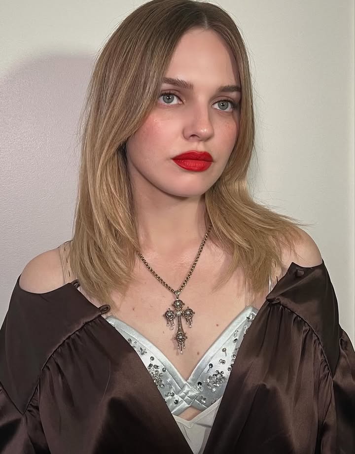 May be an image of one or more people, blonde hair, eyeliner, lipstick, makeup, necklace, top and text