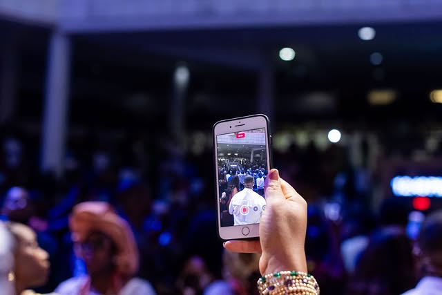 May be an image of one or more people, phone, screen, crowd and text