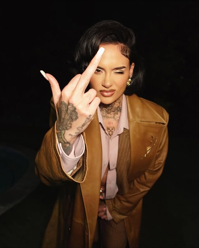 May be an image of one or more people, makeup, overcoat, fishnet stockings, bolo tie, jacket, cigarette, blazer and text