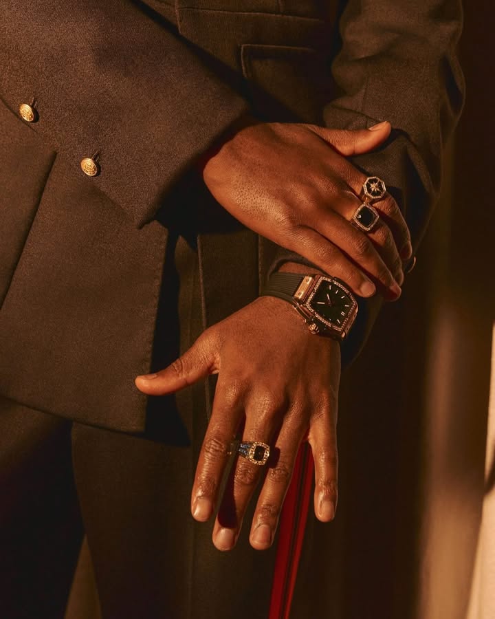 May be an image of wrist watch, suit, overcoat, blazer and text