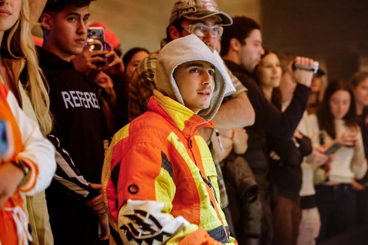 May be an image of one or more people, people racing vehicles, snowsuit, parka, crowd and text
